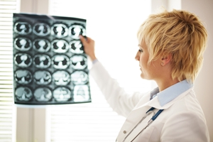 A healthcare professional with short blonde hair examines a sheet of medical X-ray images while considering a TPD Insurance Claim, standing by a window with blinds. A healthcare professional with short blonde hair examines a sheet of medical X-ray images while considering a TPD Insurance Claim, standing by a window with blinds.
