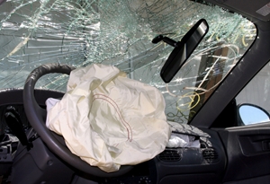 The interior of a car with a deployed airbag, shattered windshield, and broken rearview mirror suggests a recent collision or accident with potential vehicle injuries. The interior of a car with a deployed airbag, shattered windshield, and broken rearview mirror suggests a recent collision or accident with potential vehicle injuries.