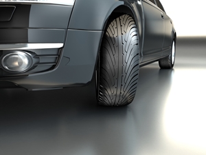 Close-up view of a sleek, modern black car focusing on the front wheel and detailed tread pattern, parked on a smooth, reflective surface—undamaged despite recent car accident Sydney headlines. Motorcycle and car collision on road