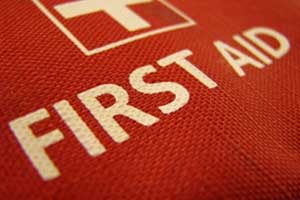 Close-up of a red first aid kit with a white cross and “FIRST AID” printed in bold white letters on the textured fabric, essential for workplaces handling work-related injuries claims. Close-up of a red first aid kit with a white cross and "FIRST AID" printed in bold white letters on the textured fabric, essential for workplaces handling work-related injuries claims.