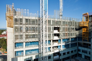 A multi-story building under construction, featuring cranes, scaffolding, exposed concrete, and partially installed glass windows under blue skies—a site where safety measures help prevent a construction accident. A multi-story building under construction, featuring cranes, scaffolding, exposed concrete, and partially installed glass windows under blue skies—a site where safety measures help prevent a construction accident.