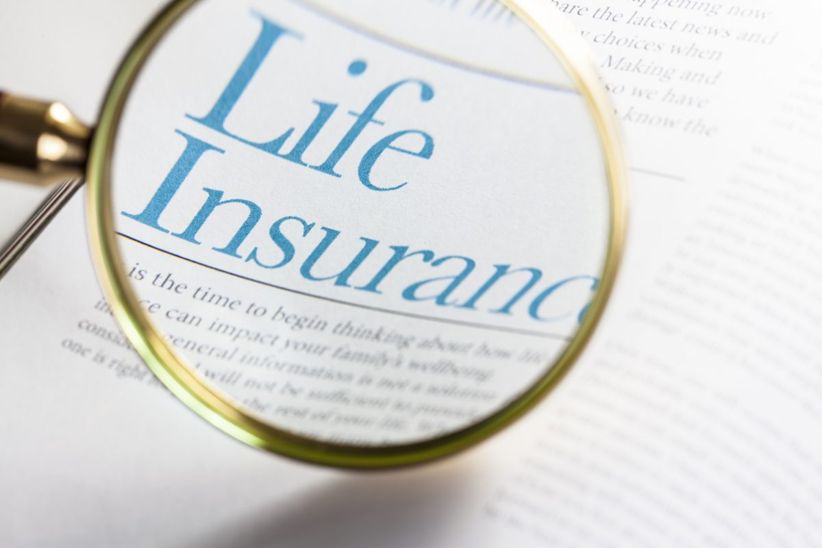 A magnifying glass highlights the words “Life Insurance” printed in blue on a document, emphasizing the topic. The surrounding text is blurred and not fully readable. A magnifying glass highlights the words “Life Insurance” printed in blue on a document, emphasizing the topic. The surrounding text is blurred and not fully readable.