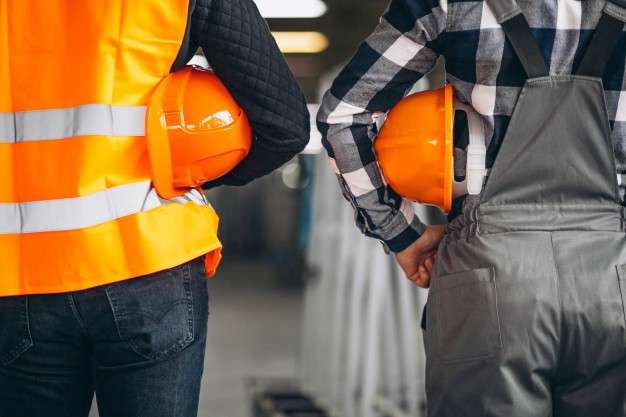 Workers’ Compensation Two construction workers in bright orange safety vests focus on their tasks, showcasing the importance of safety in construction.