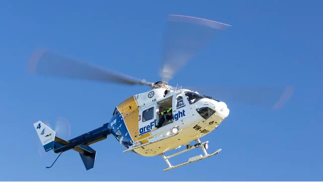 A white and blue rescue helicopter with “areflight” branding is flying against a clear blue sky, with its rotors in motion. A white and blue rescue helicopter with "areflight" branding is flying against a clear blue sky, with its rotors in motion.