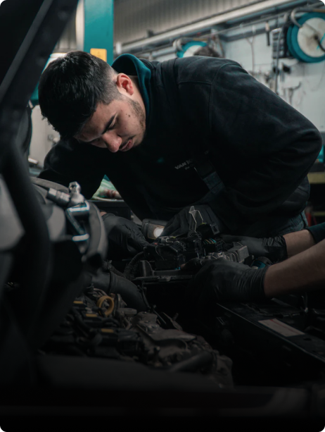 A mechanic wearing black gloves and a dark hoodie leans over a car engine, concentrating on repairs in a workshop filled with tools—a reminder of why injury compensation lawyers NSW are essential for workplace safety. A mechanic wearing black gloves and a dark hoodie leans over a car engine, concentrating on repairs in a workshop filled with tools—a reminder of why injury compensation lawyers NSW are essential for workplace safety.