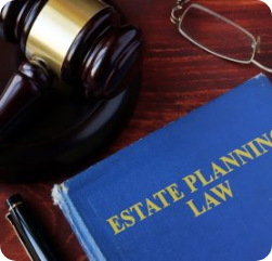 A book titled “Estate Planning Law” rests on a wooden desk next to a judge’s gavel, a pair of eyeglasses, and a black pen. A book titled "Estate Planning Law" rests on a wooden desk next to a judge's gavel, a pair of eyeglasses, and a black pen.