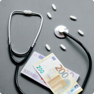A stethoscope, several white pills, and euro banknotes are arranged on a gray surface, symbolizing the connection between healthcare and financial costs.