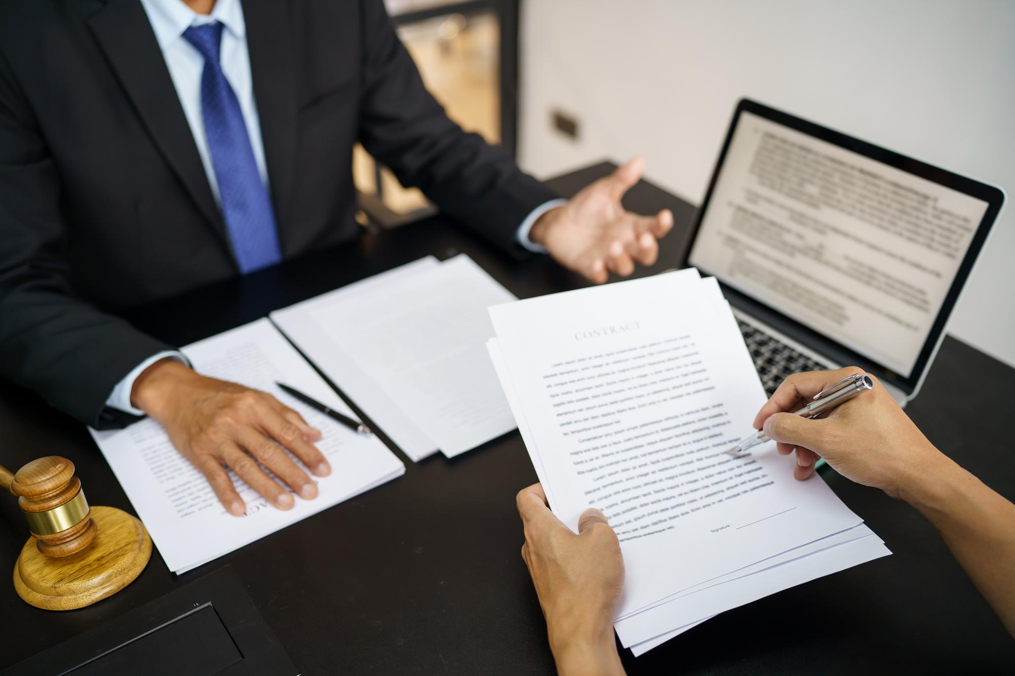 Legal counsel presents to the client a signed contract with gavel and legal law justice and lawyer concept Legal counsel presents to the client a signed contract with gavel and legal law justice and lawyer concept
