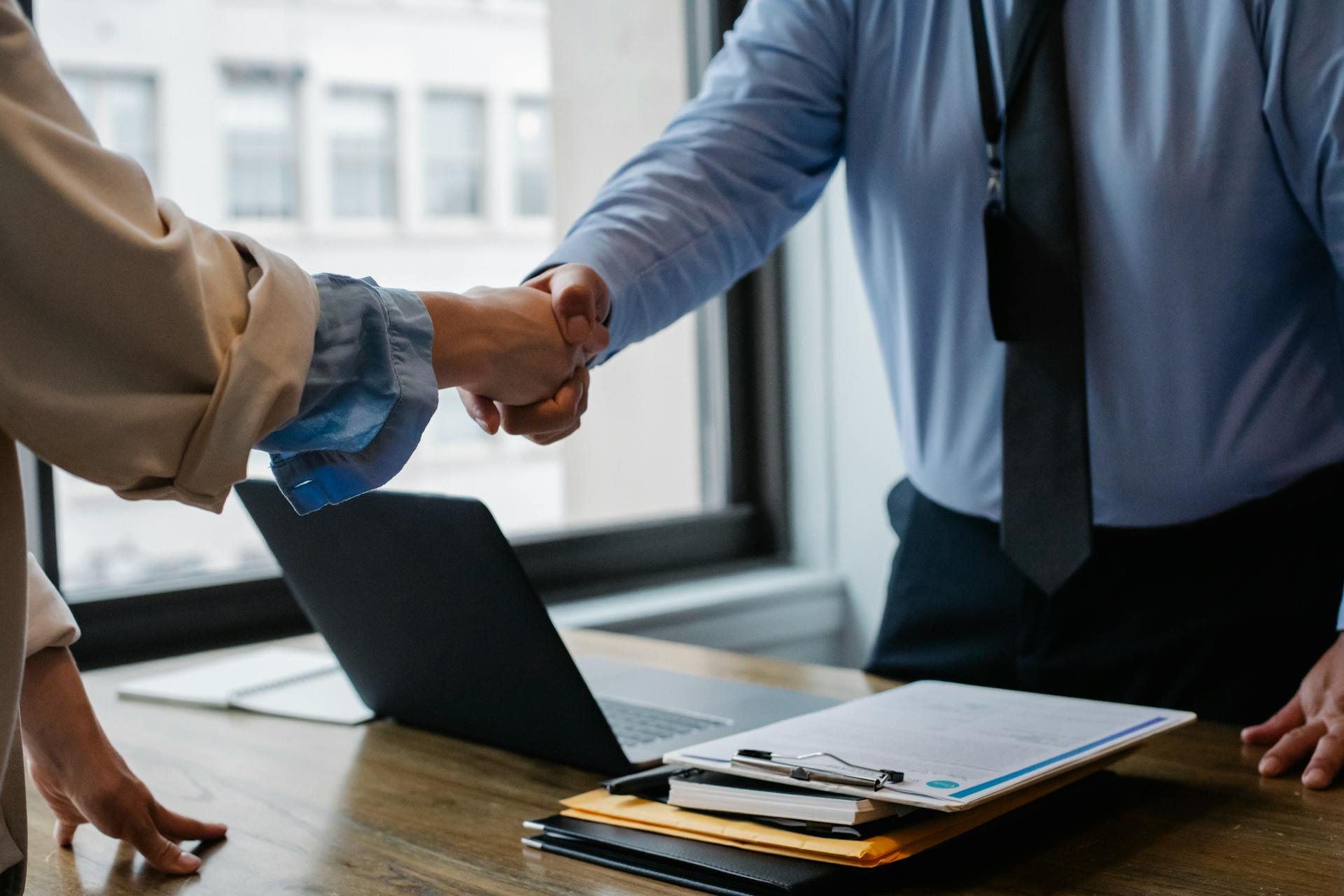 Crop colleagues shaking hands in office Crop colleagues shaking hands in office